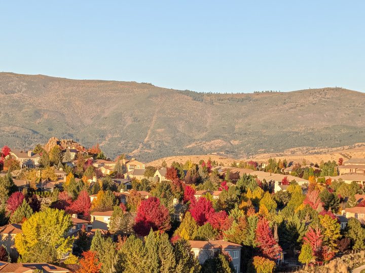 Somersett homes among bright fall trees below the foothills on a clear morning.